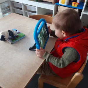 On peut voir un de mes élèves prendre une photo d'un panda en plastique à l'aide de l'appareil photo de la tablette.