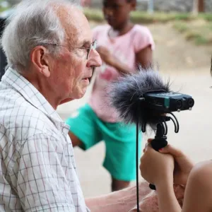 Photographie d'un enfant participant à l'atelier tenant un microphone à un sénior qui lui raconte quelque chose