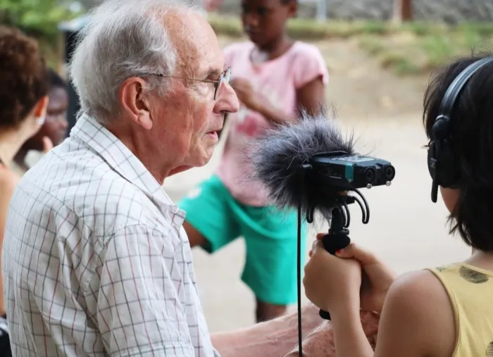 Photographie d'un enfant participant à l'atelier tenant un microphone à un sénior qui lui raconte quelque chose